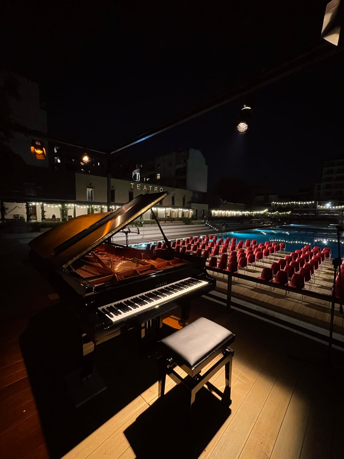 Pianoforte a coda su un palco all’aperto, di sera, davanti alla platea