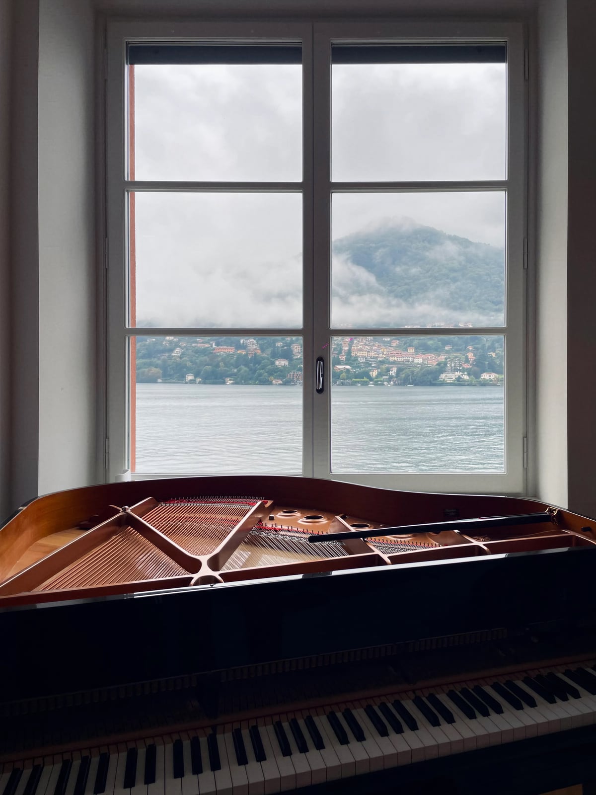 Pianoforte a coda davanti a una grande finestra con vista sul lago