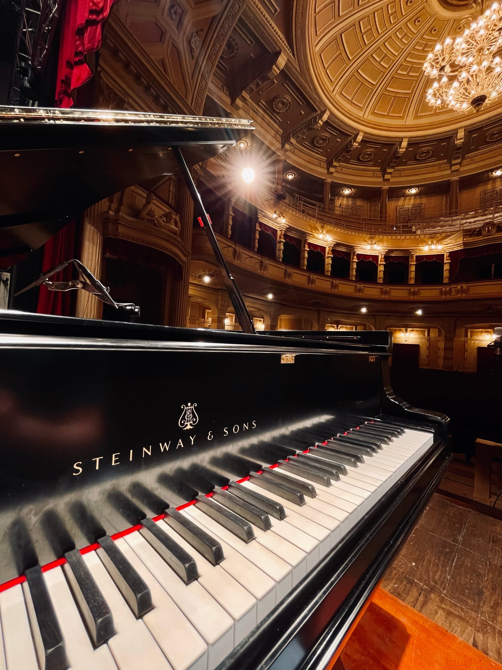 Pianoforte a coda Steinway & Sons sul palco di un teatro storico, con la cupola dorata e il lampadario sullo sfondo